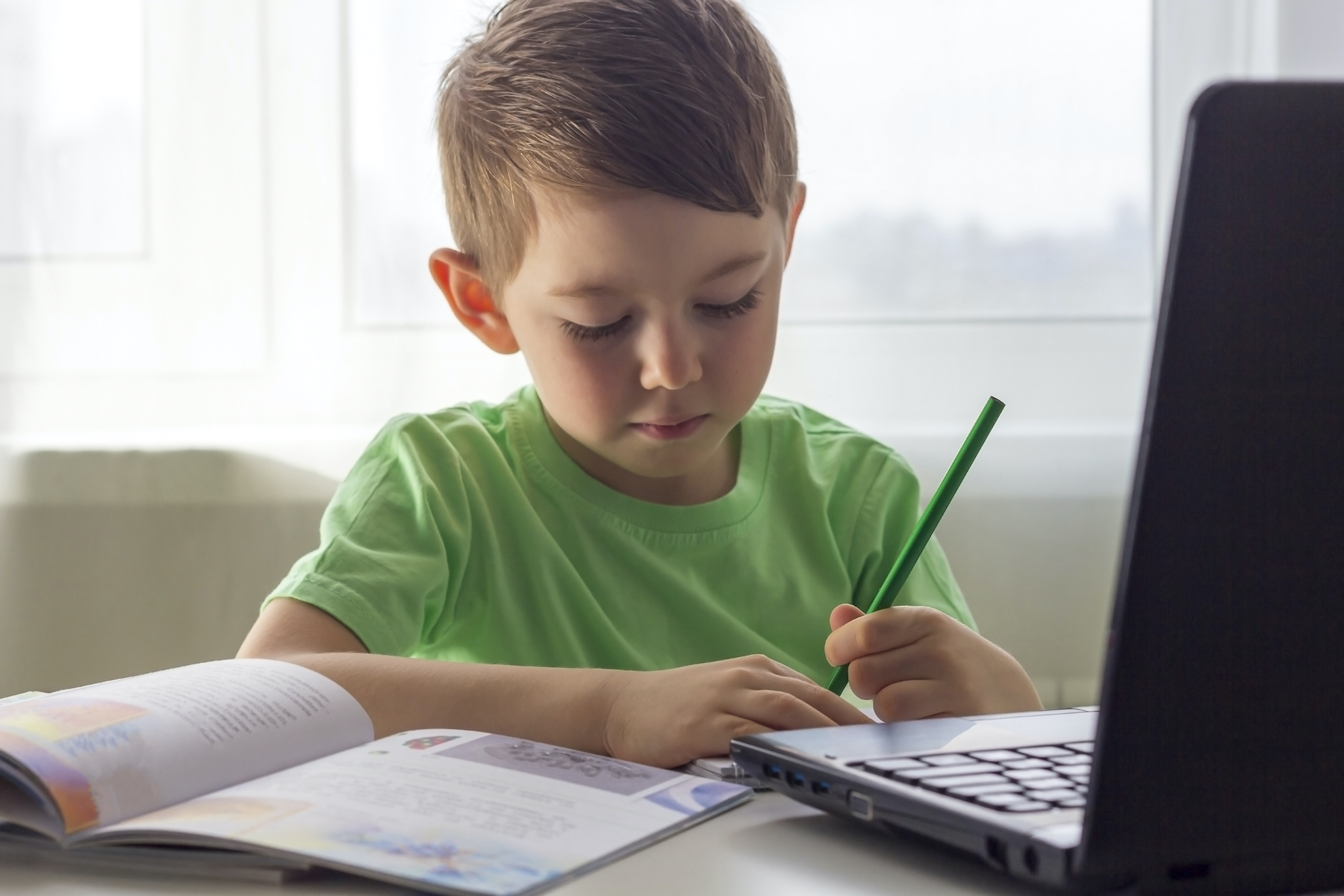 Distance learning, online education. Social distance and self-isolation during quarantine. Preschooler or schoolboy studying at home with notebook and doing homework for development school.
