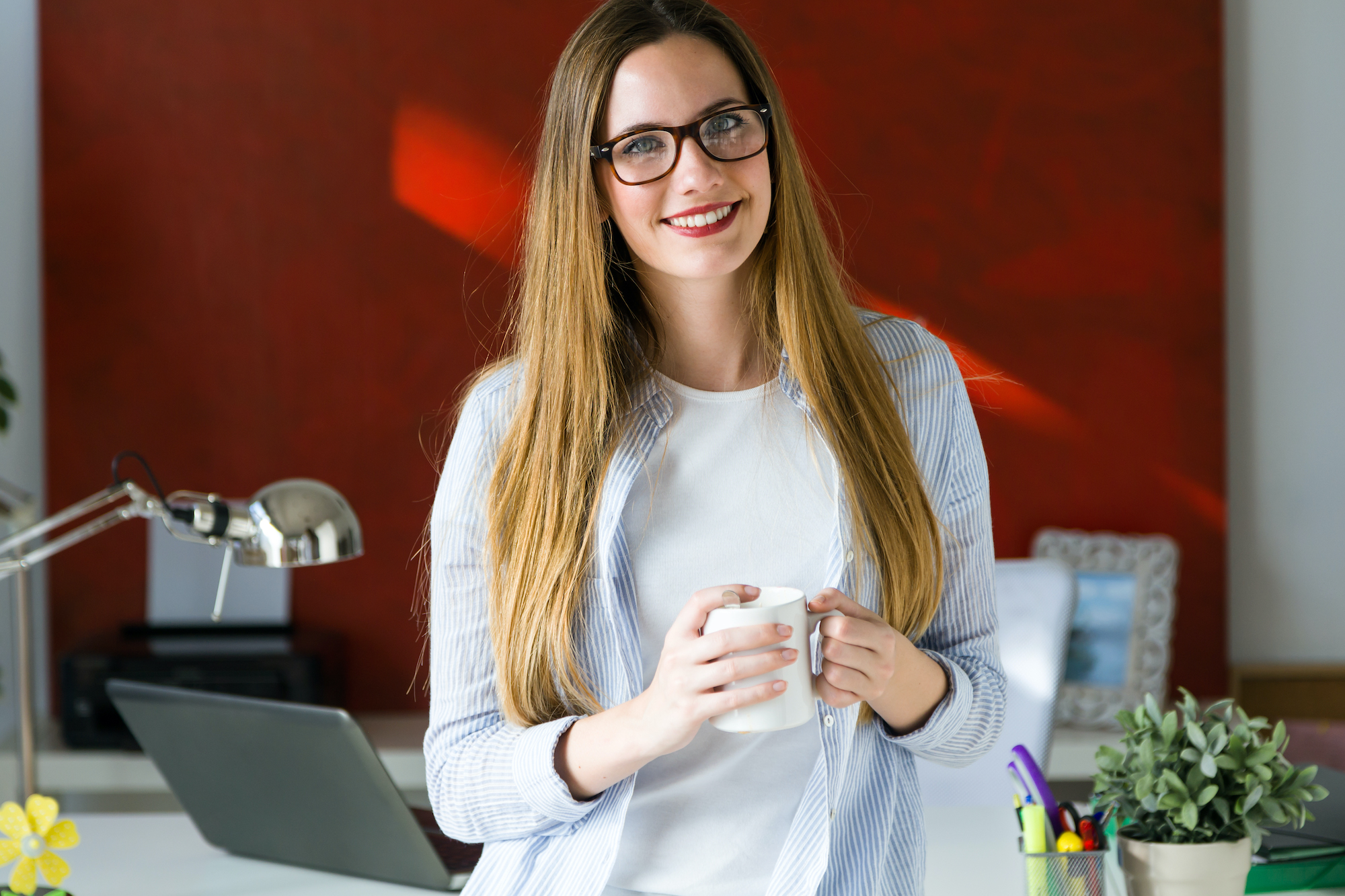 Beautiful young woman drinking coffee in the office.